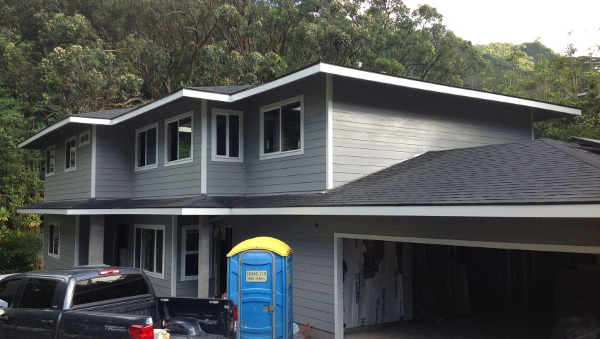 A portable toilet near a grey colored house