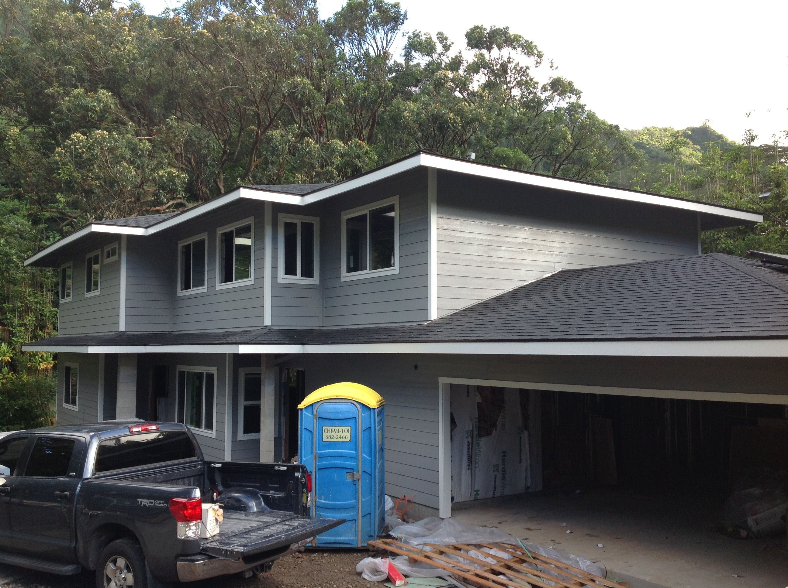 A portable toilet near a grey colored house