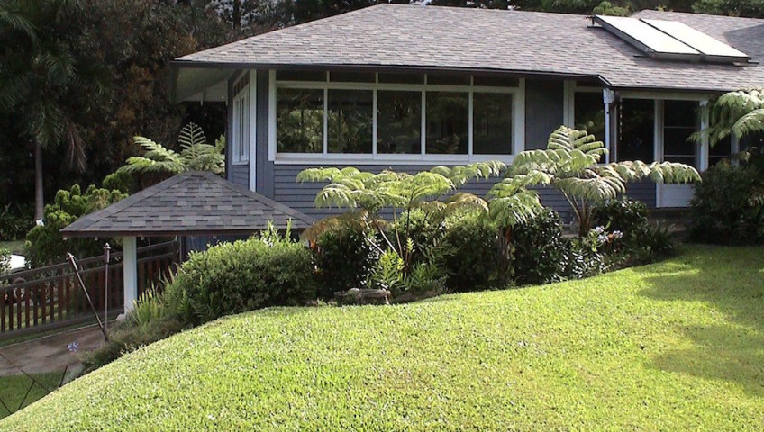 A grey house with slanting roof surrounded by trees