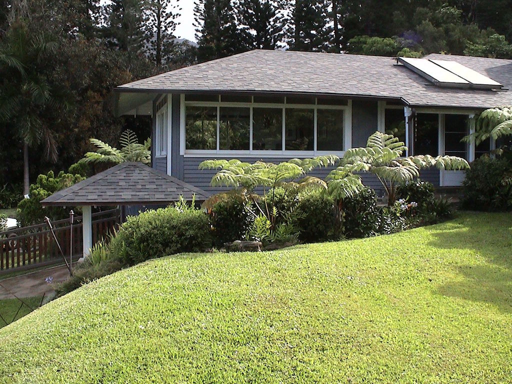 A grey house with slanting roof surrounded by trees